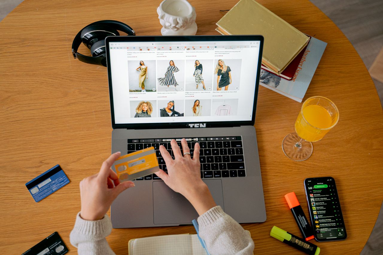 The Art of Drawing Readers In: Your attractive post title goes here Hands holding credit card making online purchase on laptop at wooden desk with various items.
